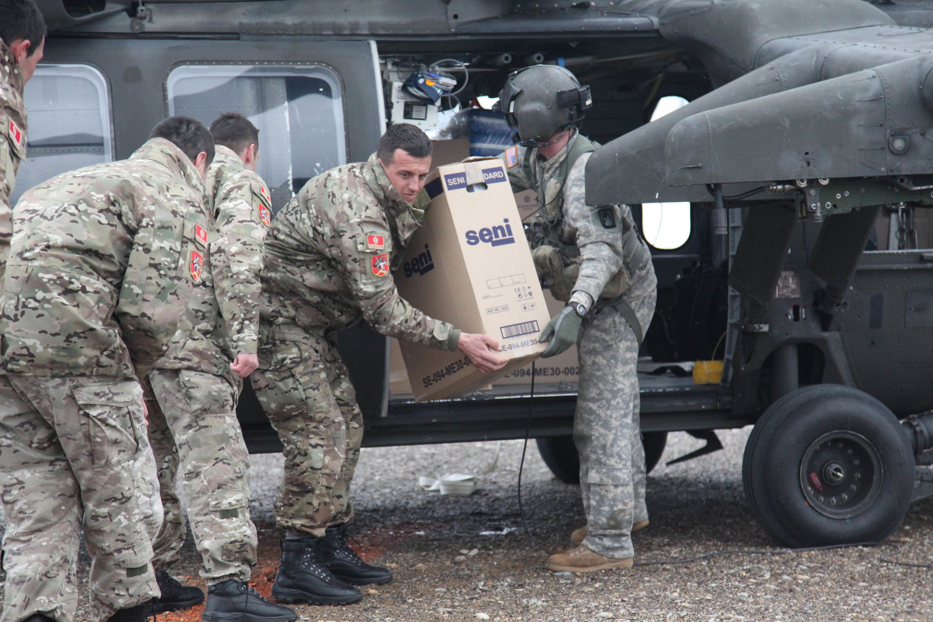 A U.S. Army soldier (right) hands a box of humanitarian relief …