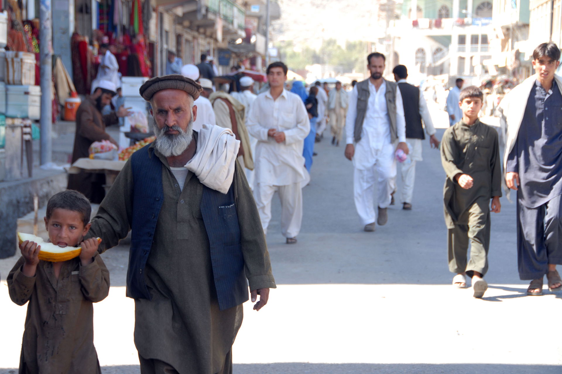 An Afghan father and his child walk down the street from the lo…