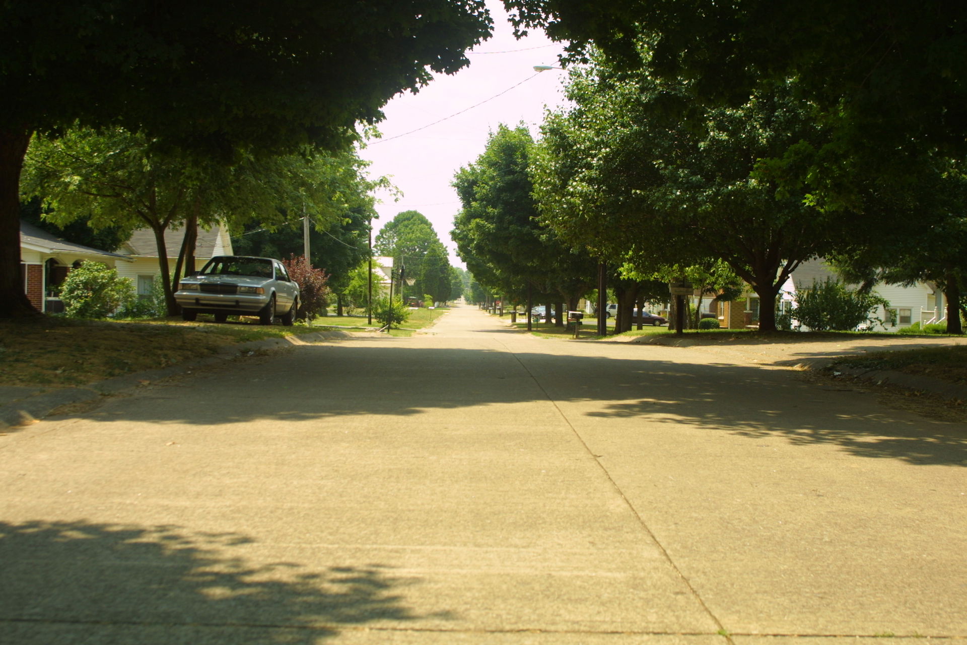 View down a residential road with parked cars in Cave City, KY