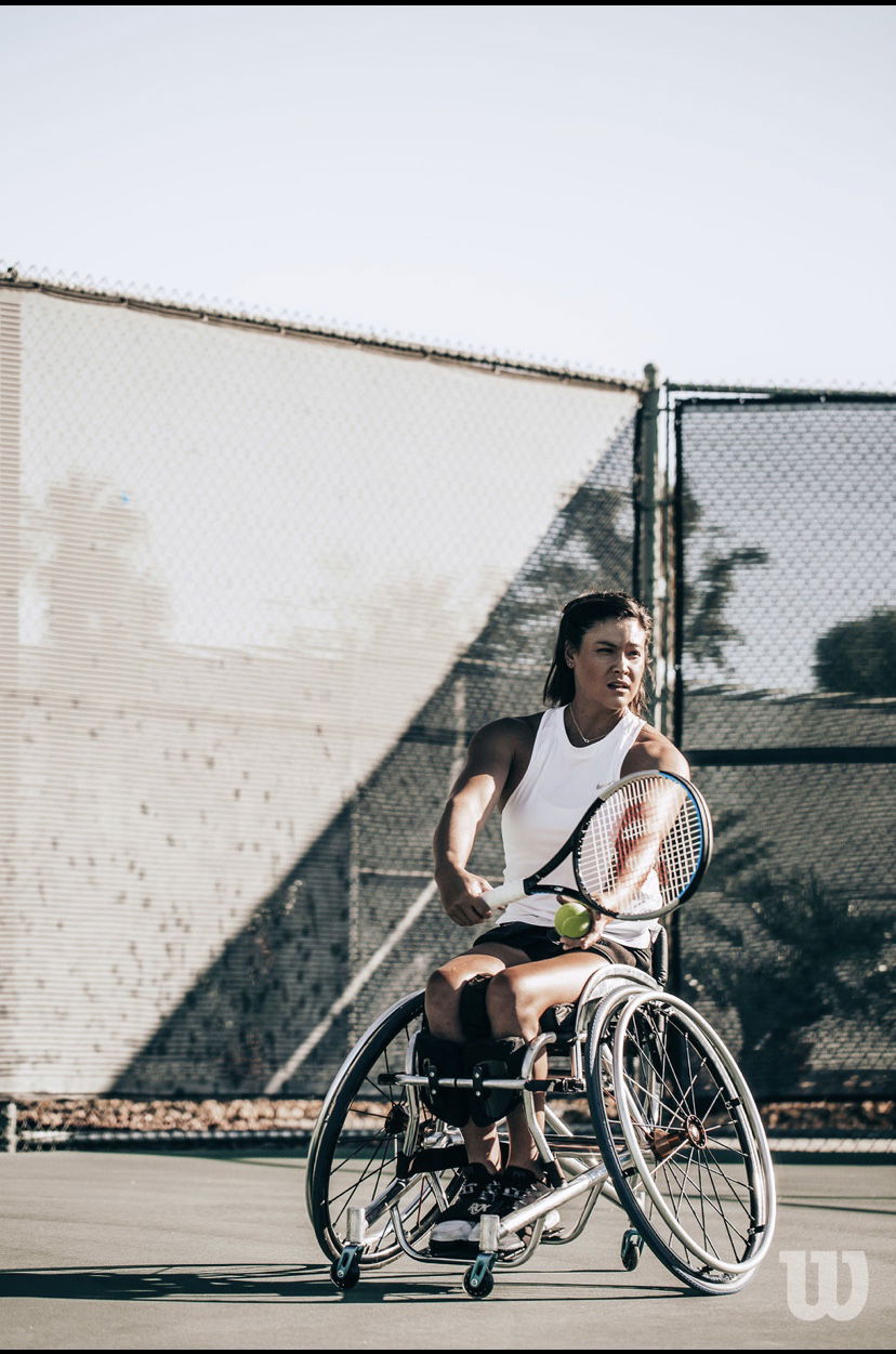 Dana Mathewson wearing a white tanktop serving the ball on the …