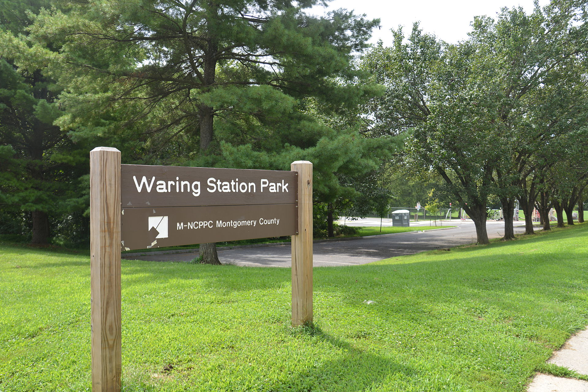 The sign for Gunners Lake Park with trees and parking lot behin…