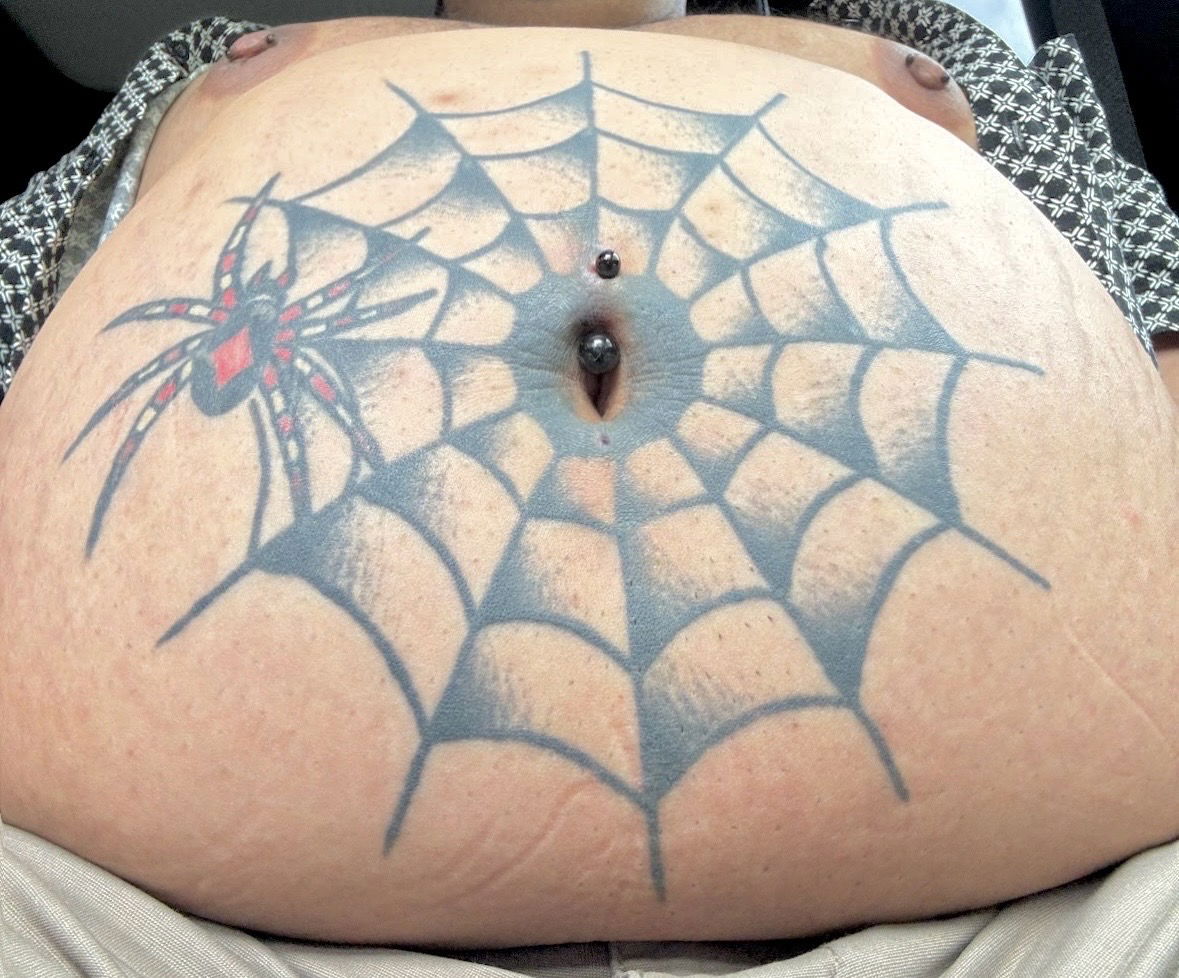 A tattoo and piercing—utilizing a curved barbell—on a person’s …