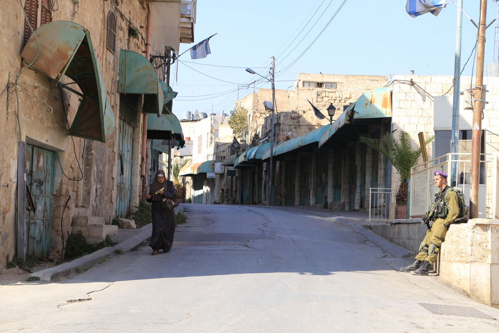 A soldier stationed at a checkpoint on al-Shuhada Street. The c…
