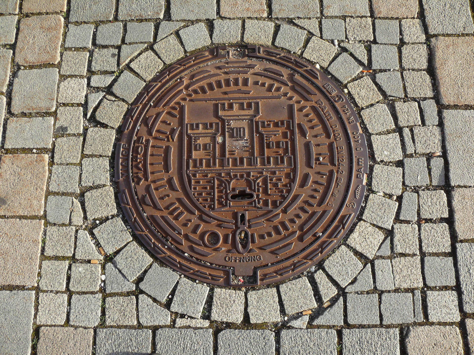 Weilheim, Marienplatz: Kanaldeckel mit dem Stadtwappen