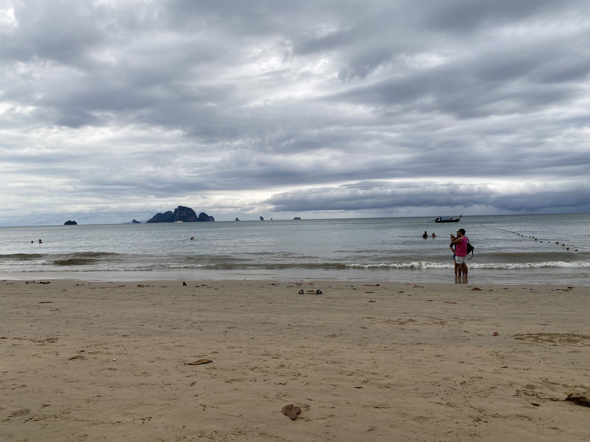 The beach is seen with one man trying to fish. It is a cloudy g…