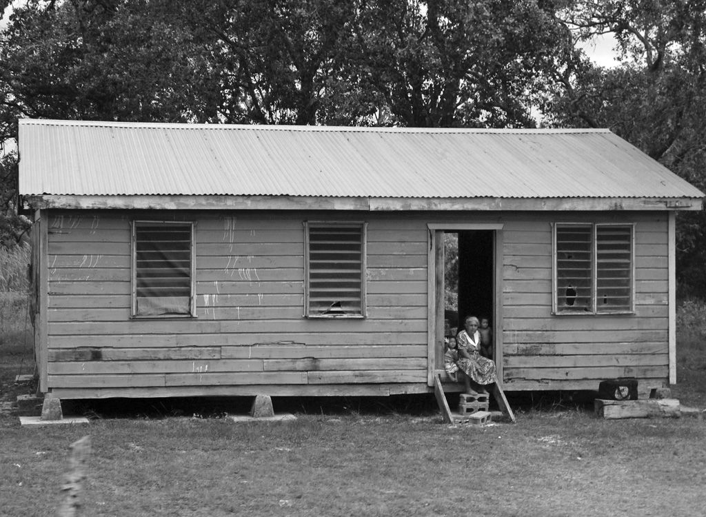 A gray-haired woman and two young children sit in the doorway o…