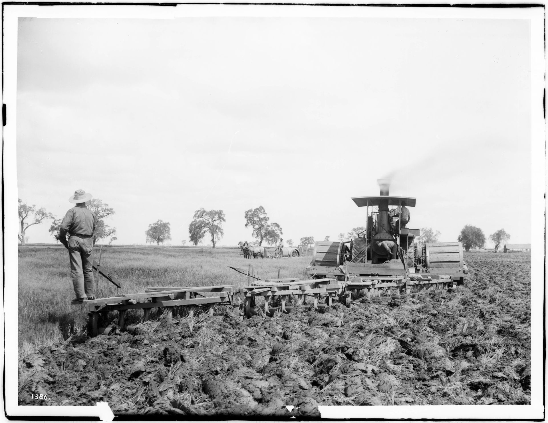 Three men operating a steam plow in a field in Hanford, Kings C…