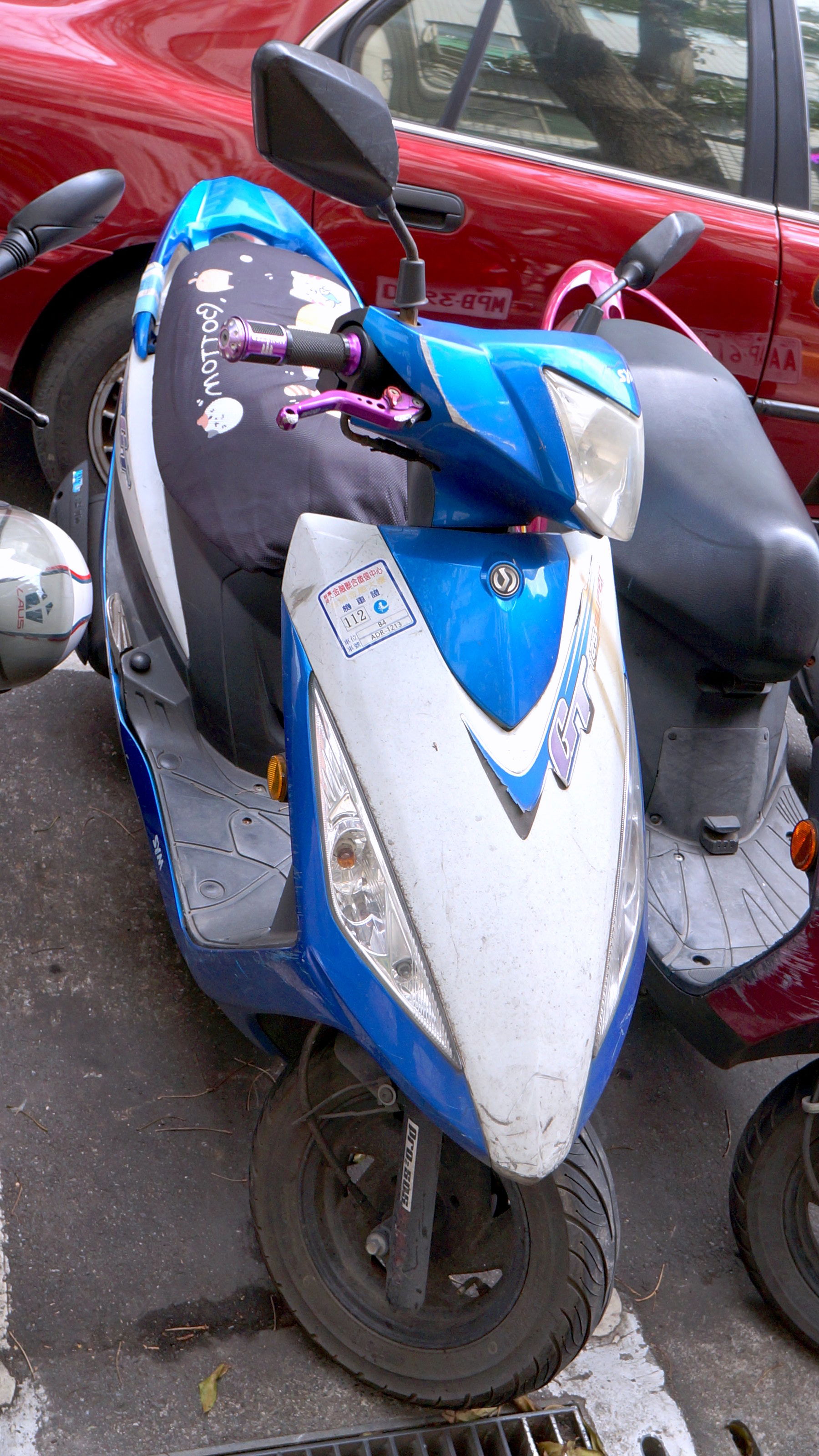 ​三陽GT125 Super機車ADR-1213車頭，停靠臺北市中山區德惠街，左上角貼金融聯合徵信中心台開金融大樓機車停車證。