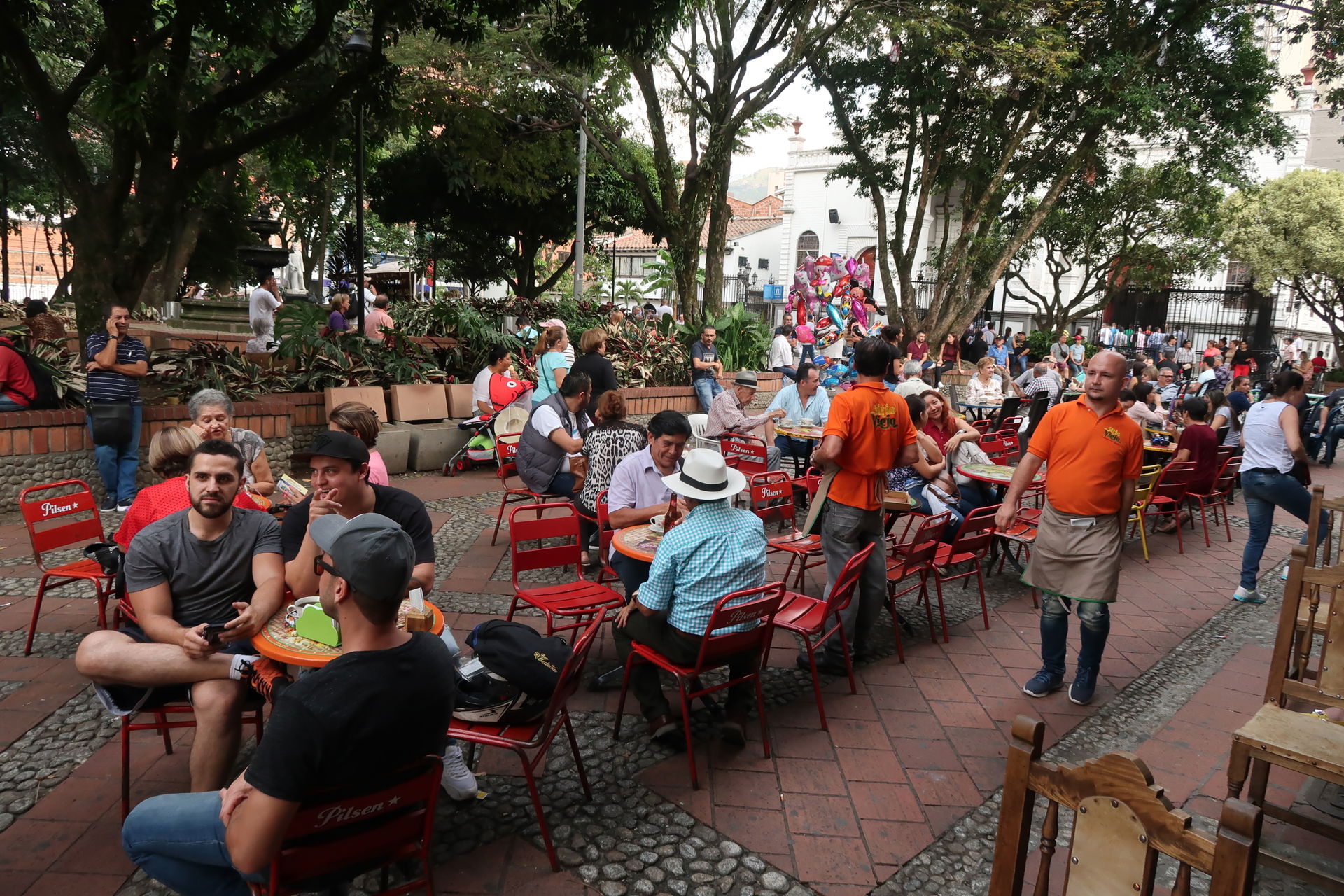 Residents and visitors sit in outside a pub in Sabaneta Parque