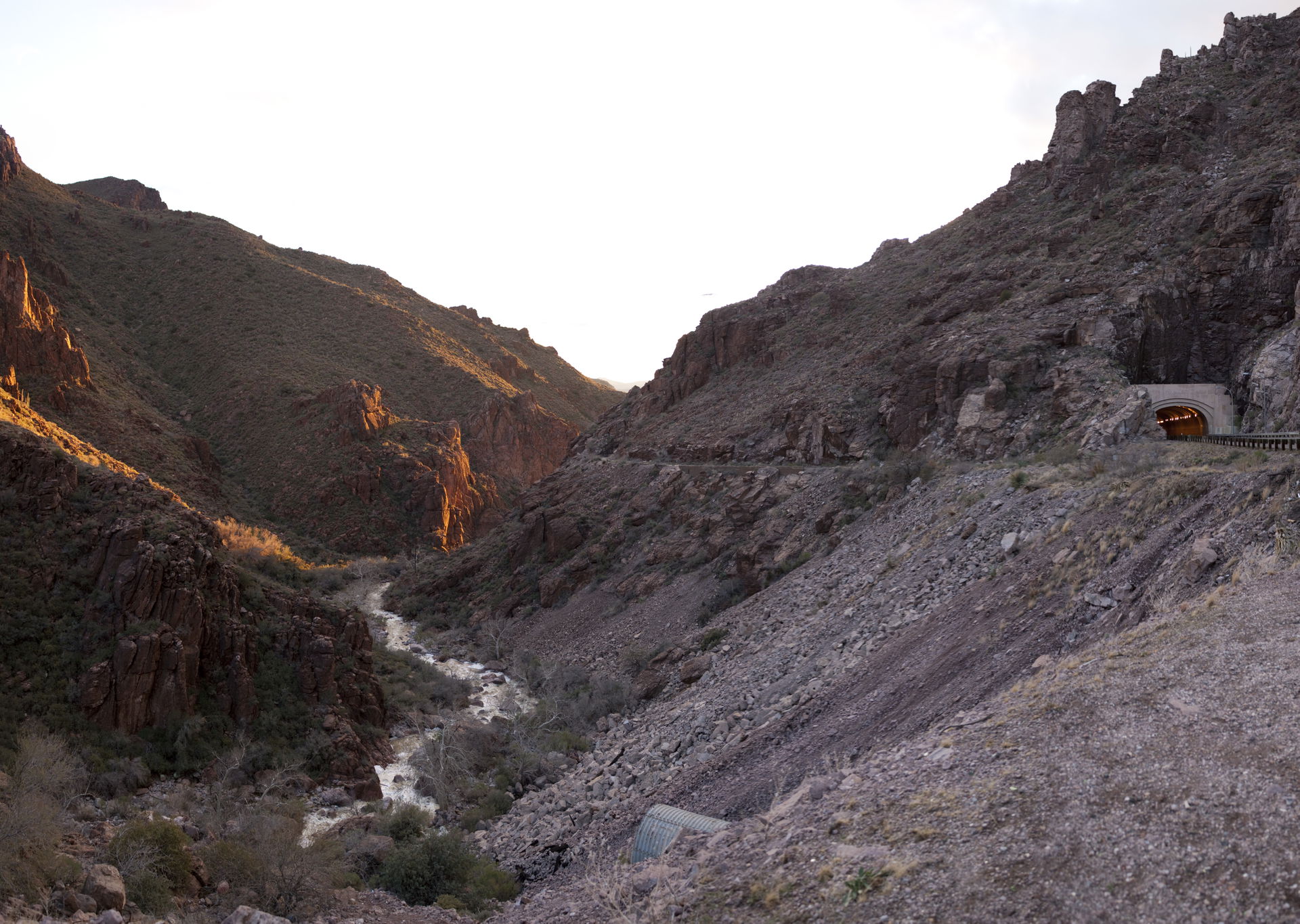 As the sun sets, Queen Creek flows next to US-60 between the to…