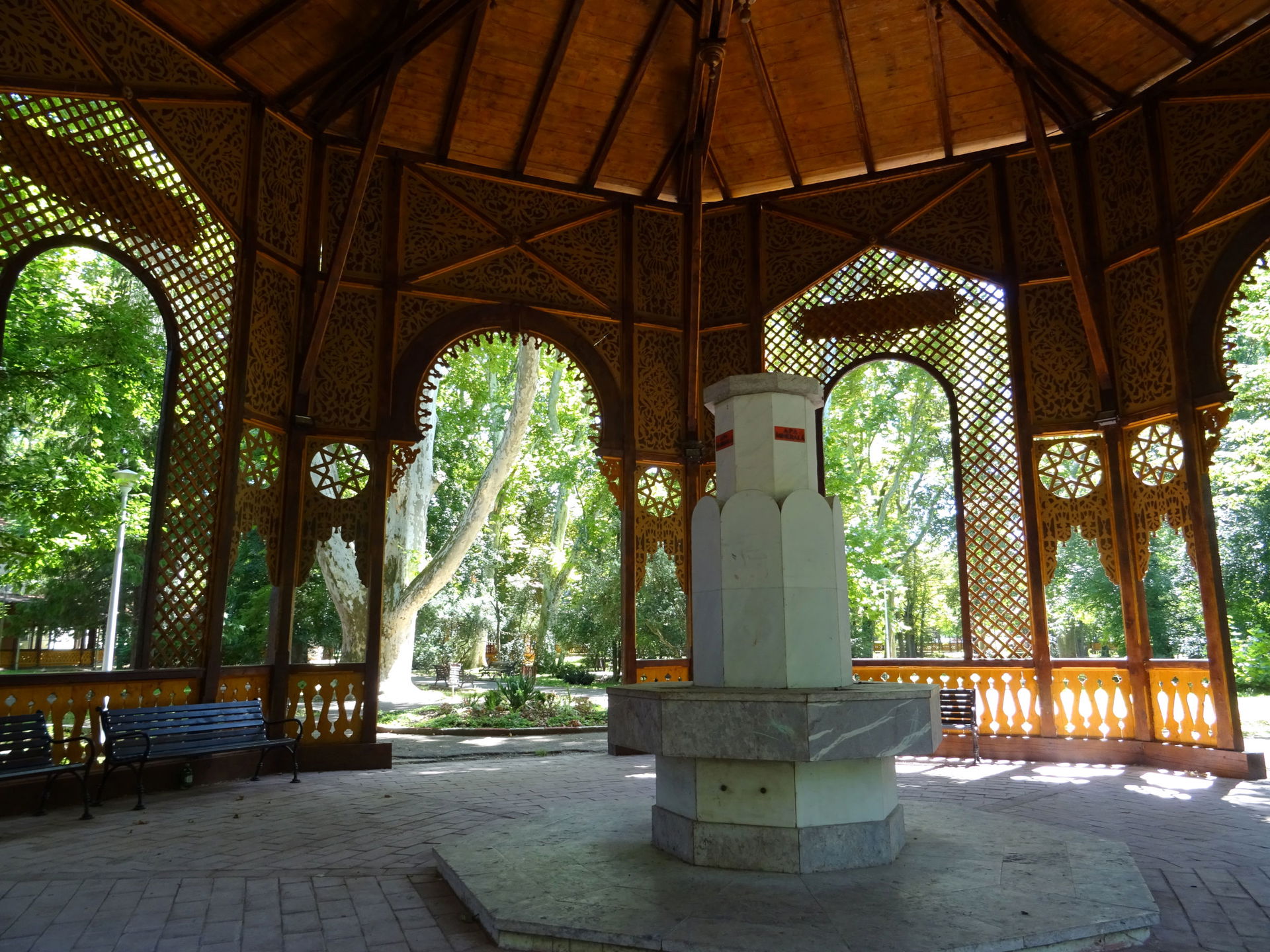 Byzantine style wooden colonnade in Buzias park, fountain
.mw-p…