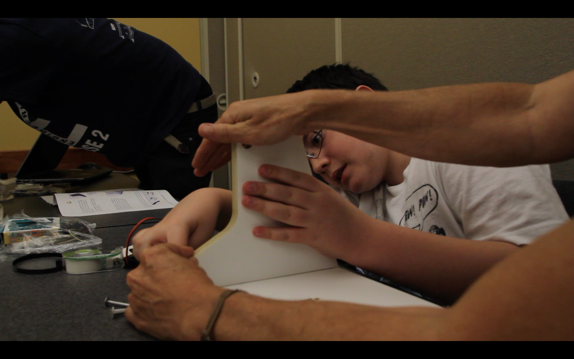 A student and their mother team up to assemble a heliostat.