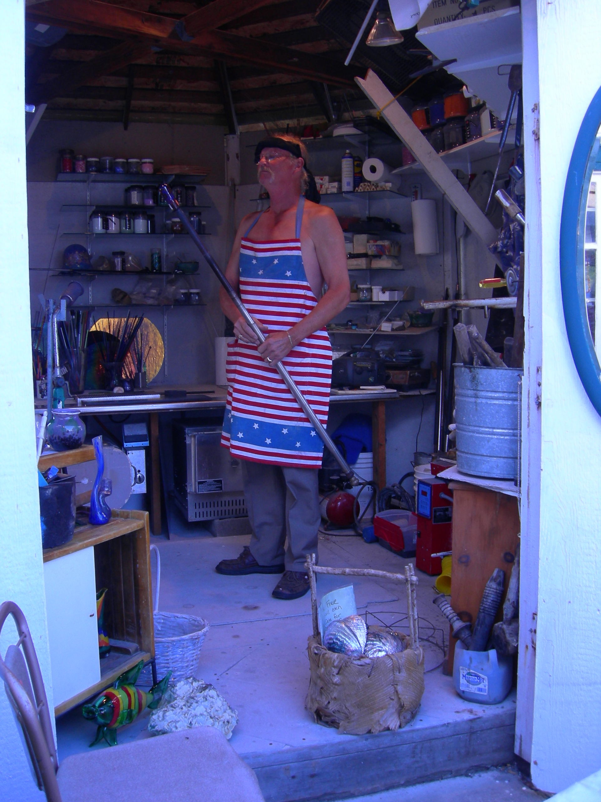 Glassblower working in a small building behind an art gallery i…