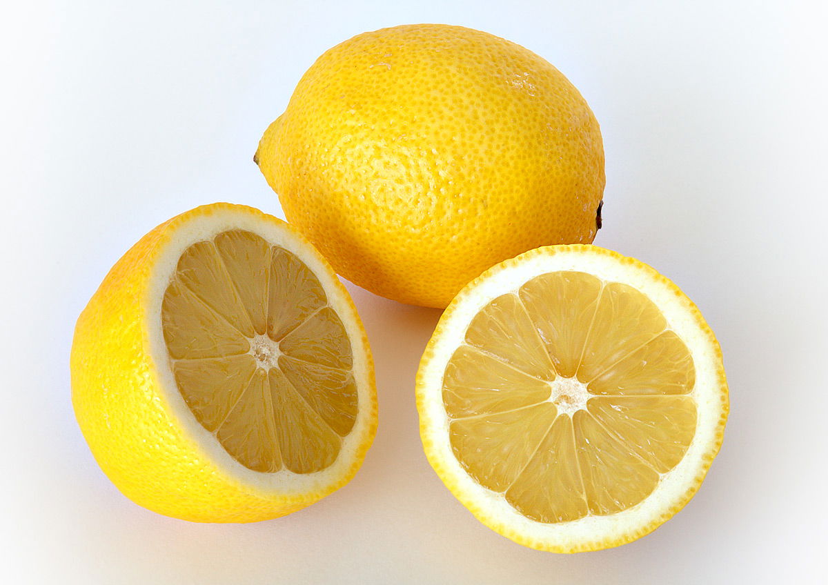 This image shows a whole and a cut lemon.