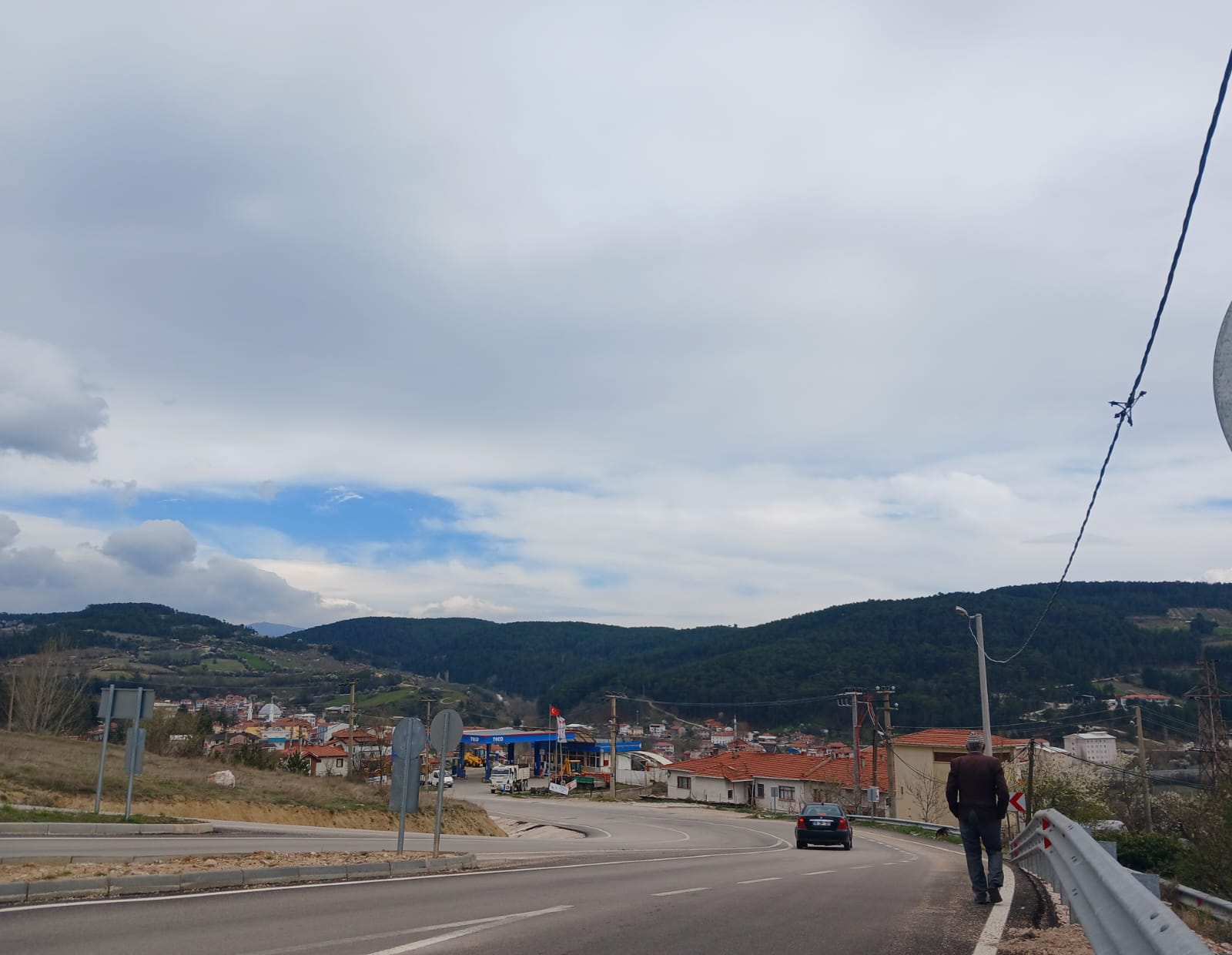 Beneath the vast sky, where green and blue meet, a small town s…