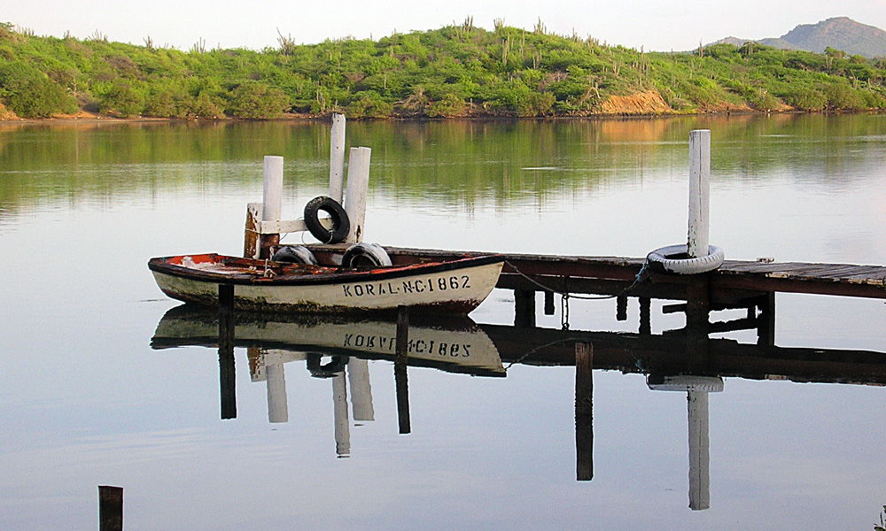 In the early morning, a fishing skiff remains docked on the wat…
