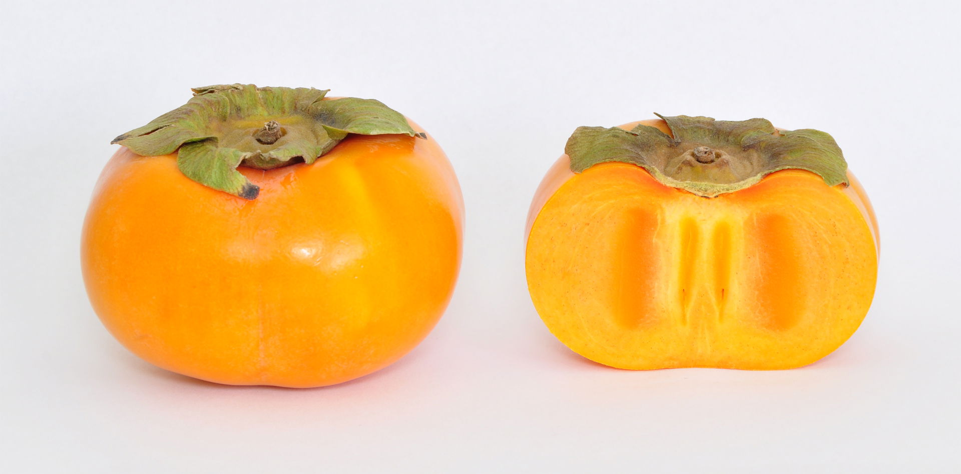 A whole Jiro Persimmon (Diospyros Kaki) and a sliced one.