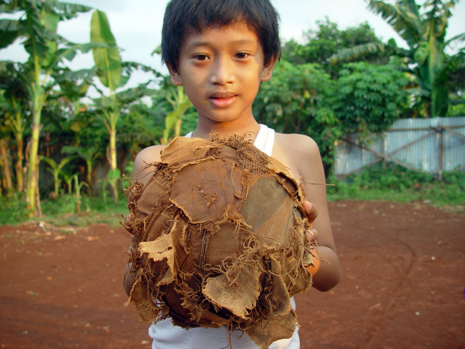 A young boy, in Jakarta Indonesia, holds a tattered football (s…