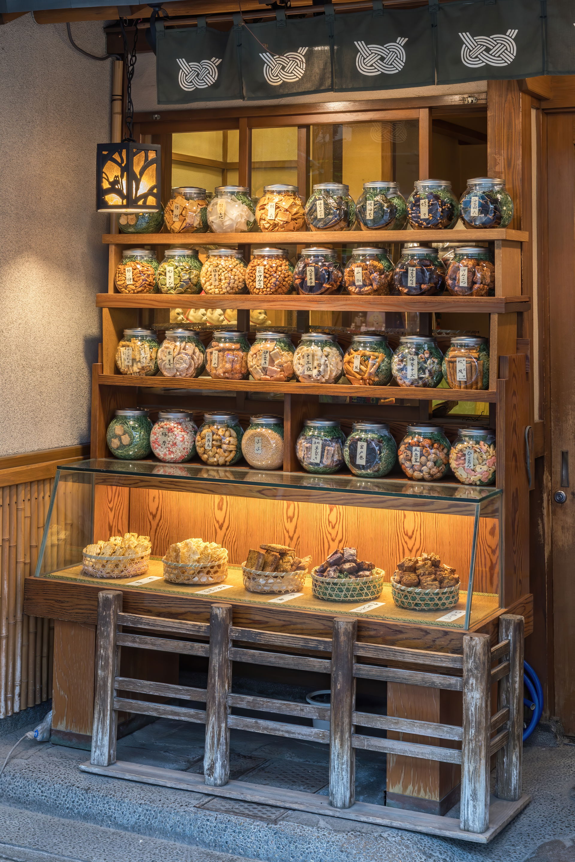 Illuminated wooden shelf with many glass jars containing cookie…
