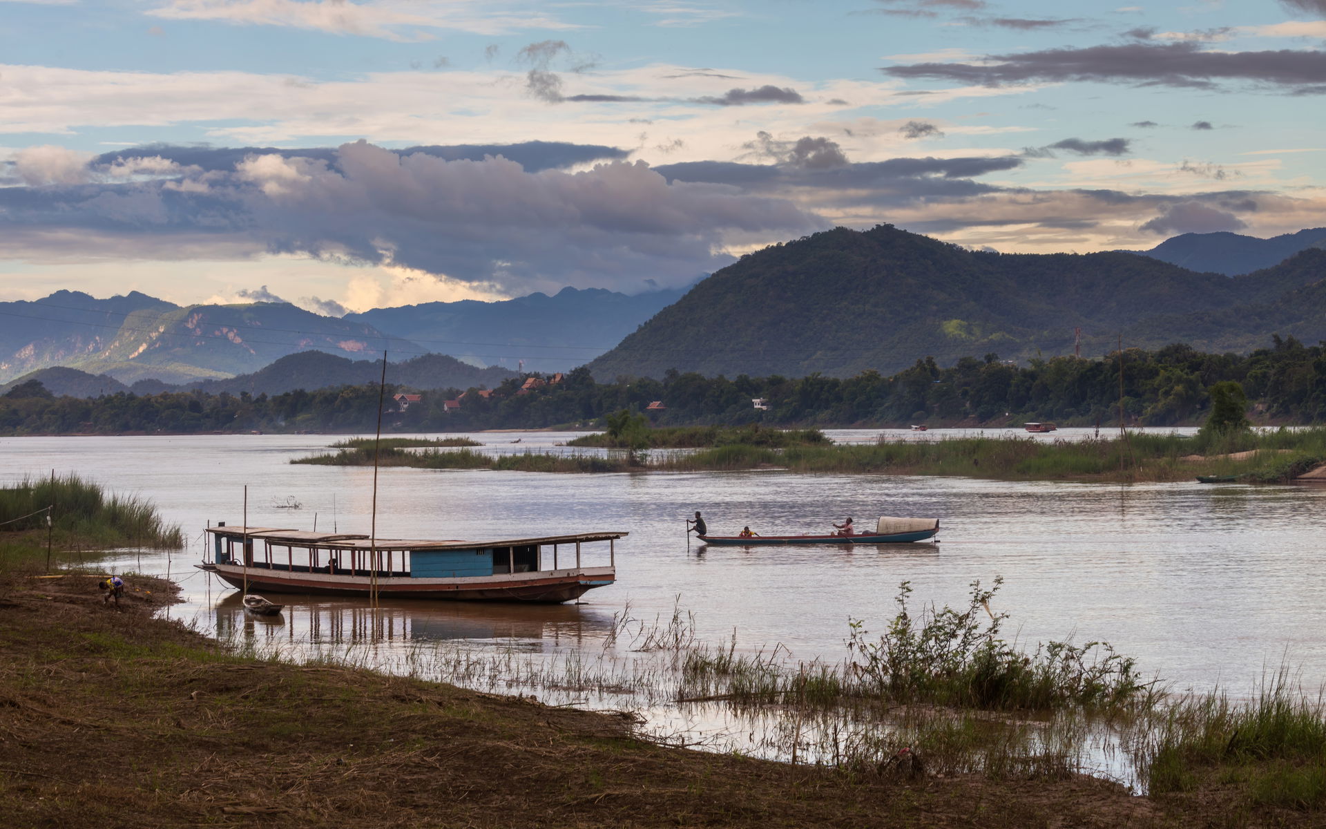 Pirogue and boat on the Mekong with colorful sky at sunset in L…