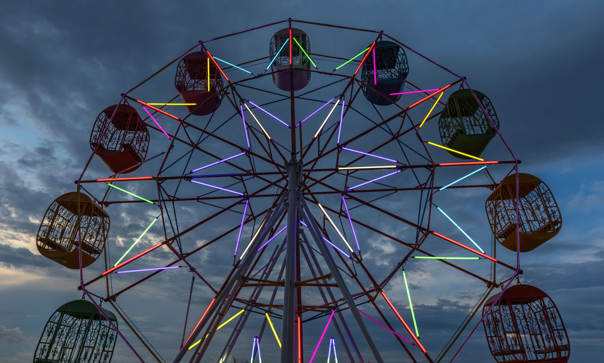 Illuminated Ferris wheel at dusk in a funfair in front of the M…