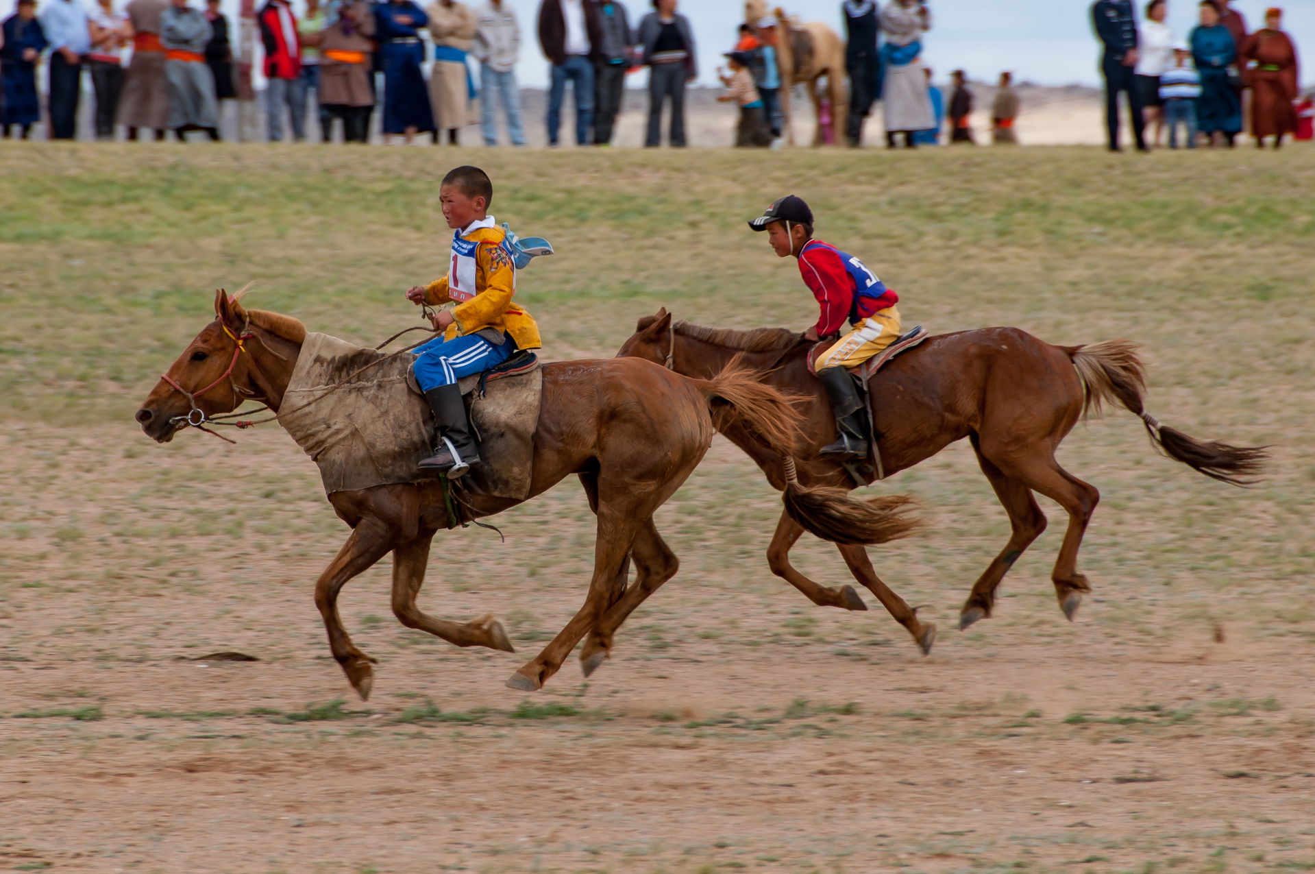 Two young riders race across the finish line in a Naadam horse …