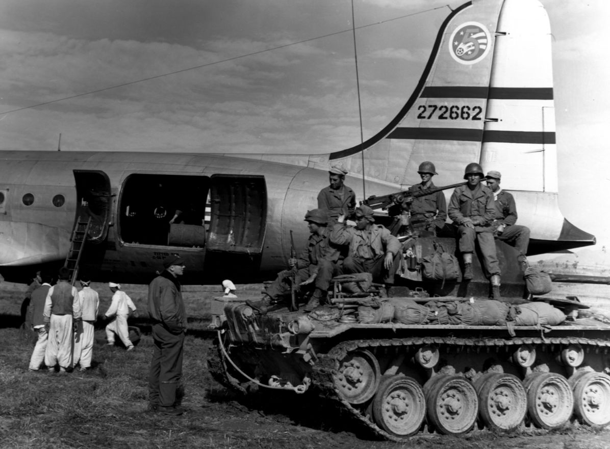 A Fifth Air Force Douglas C-54 unloading drums of oil at Sinmak…
