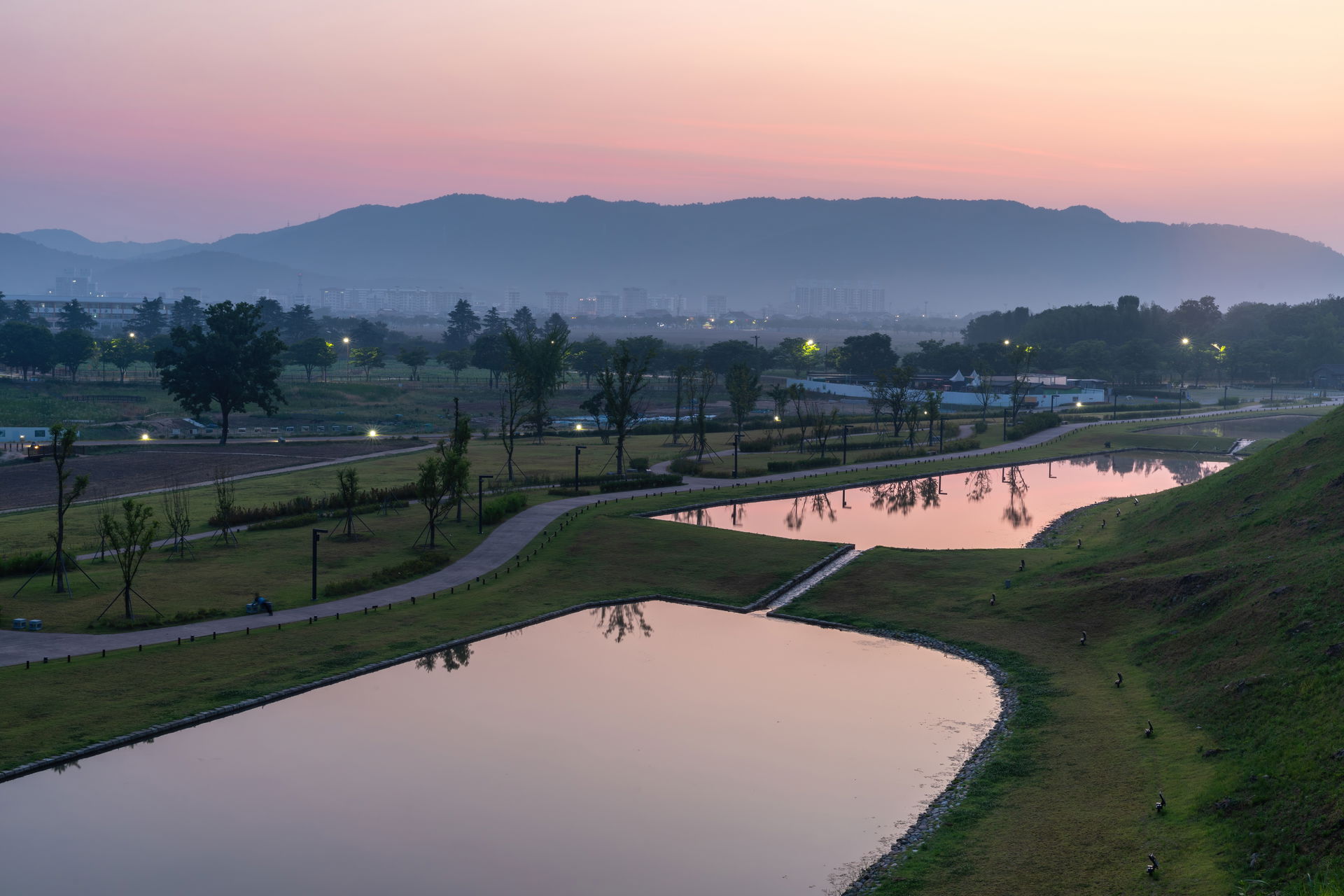 Pink sunrise over ponds in the Tumuli Park of Gyeongju Historic…