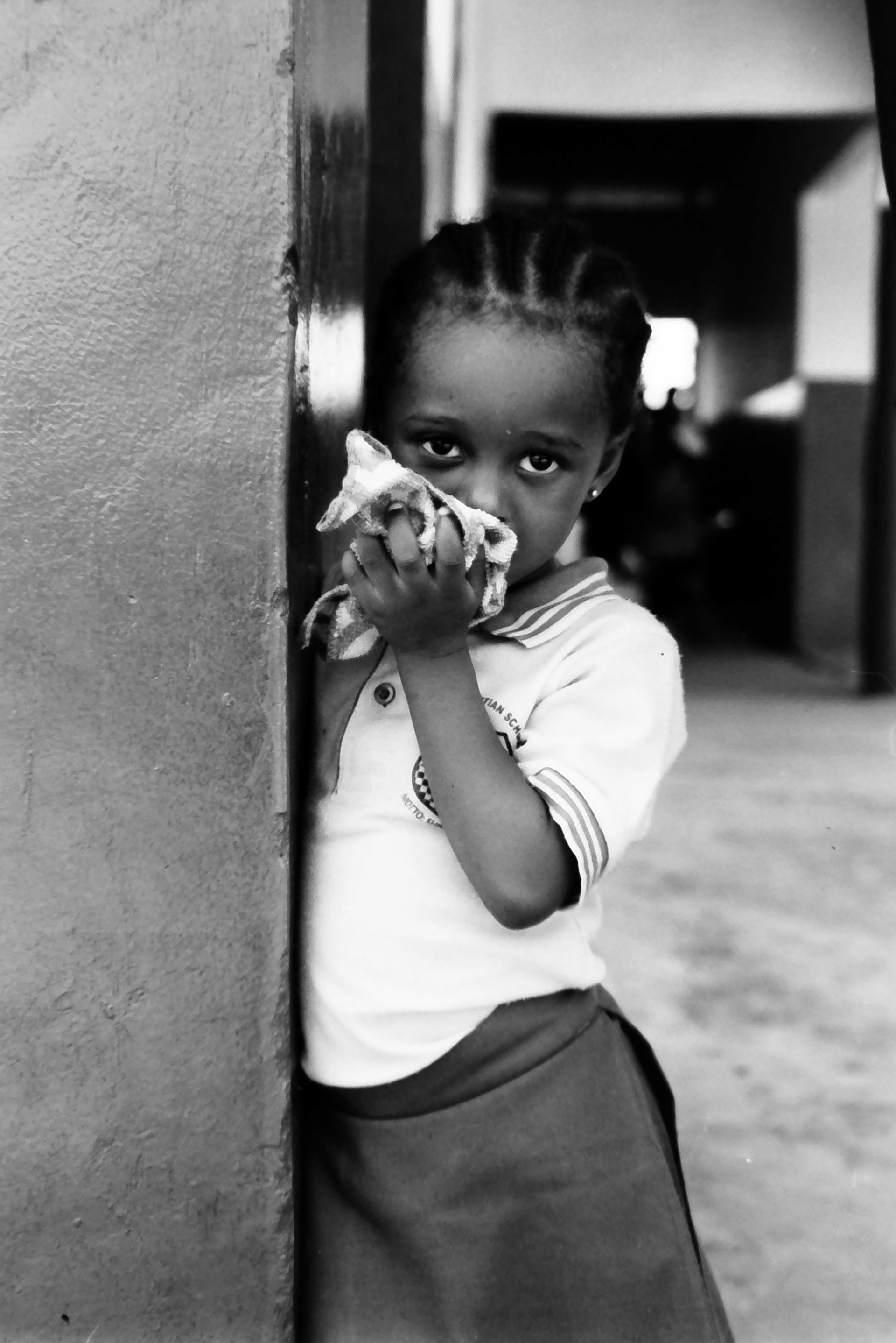 This black-and-white photograph captures a young child standing…