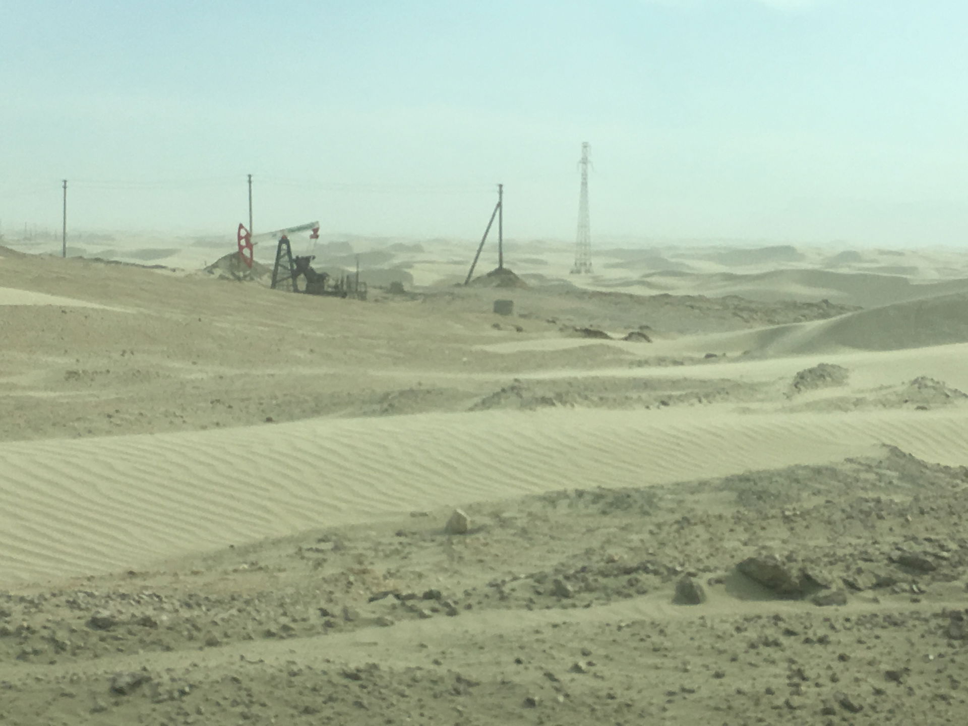 Photo of an oil well donkey among the sand dunes of the Cheleke…