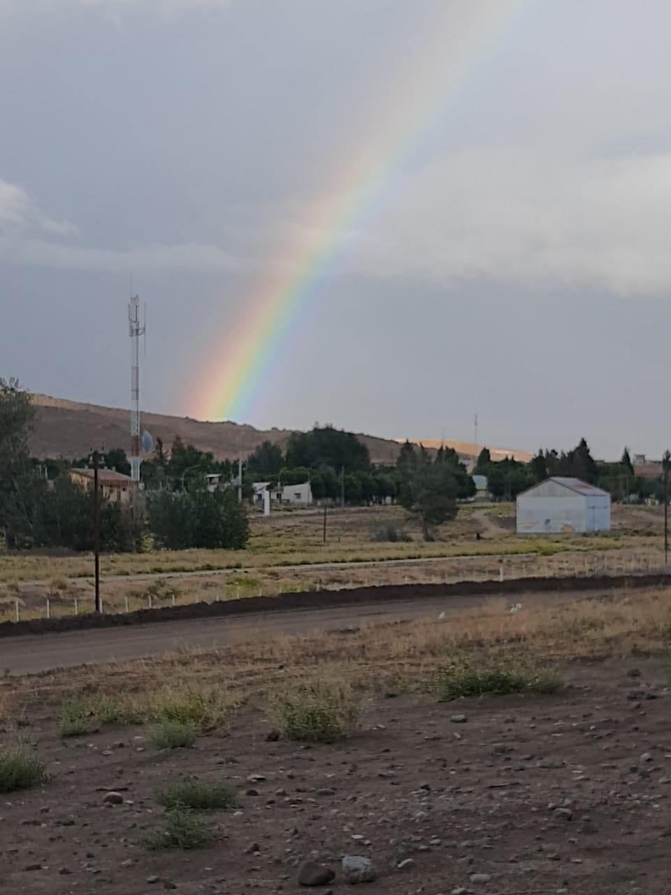 Foto de Comallo en terreno del ferrocarril con arco iris de fon…