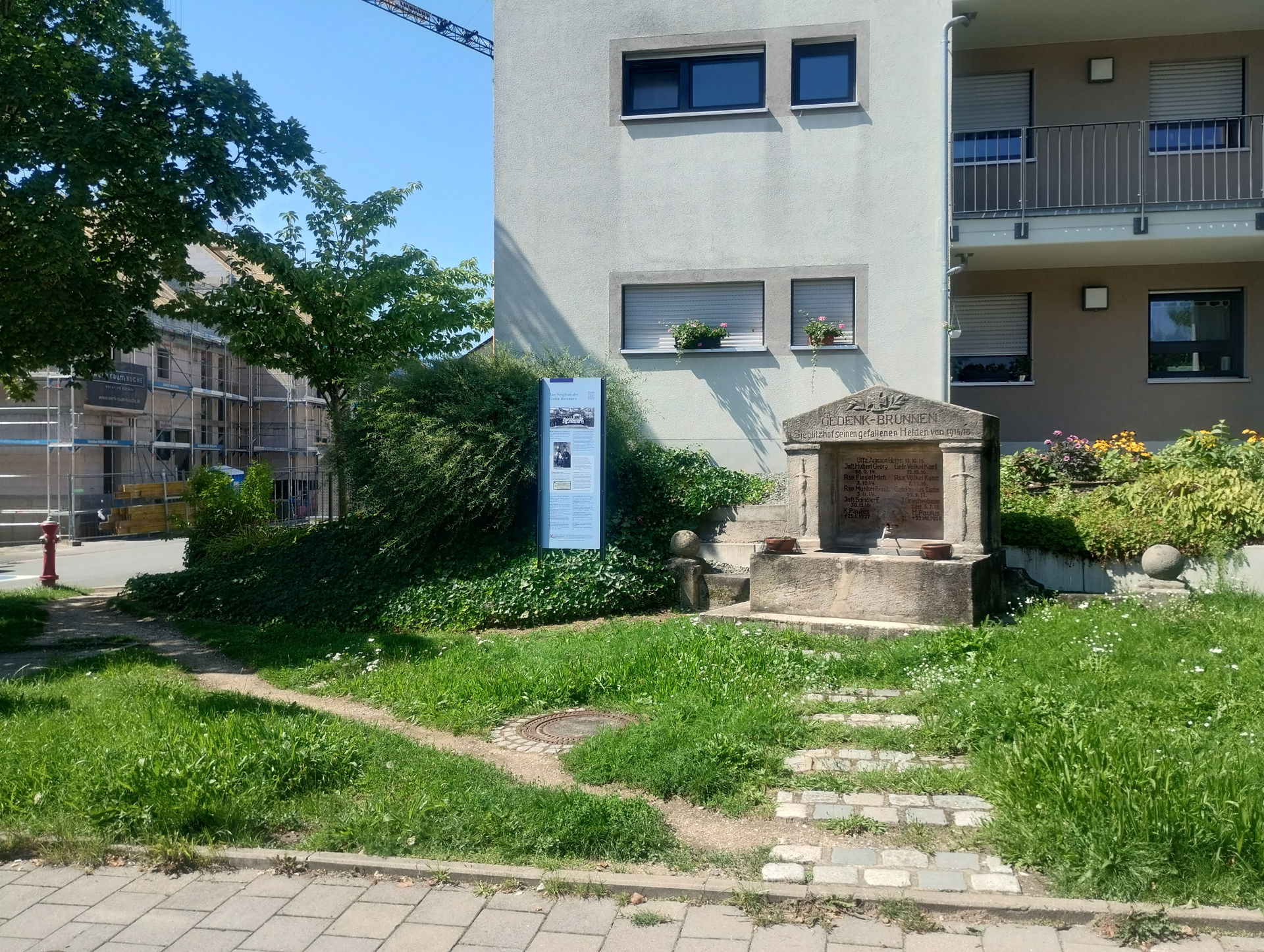 Gesamtansicht des Gedenkbrunnens in Sieglitzhof mit Information…