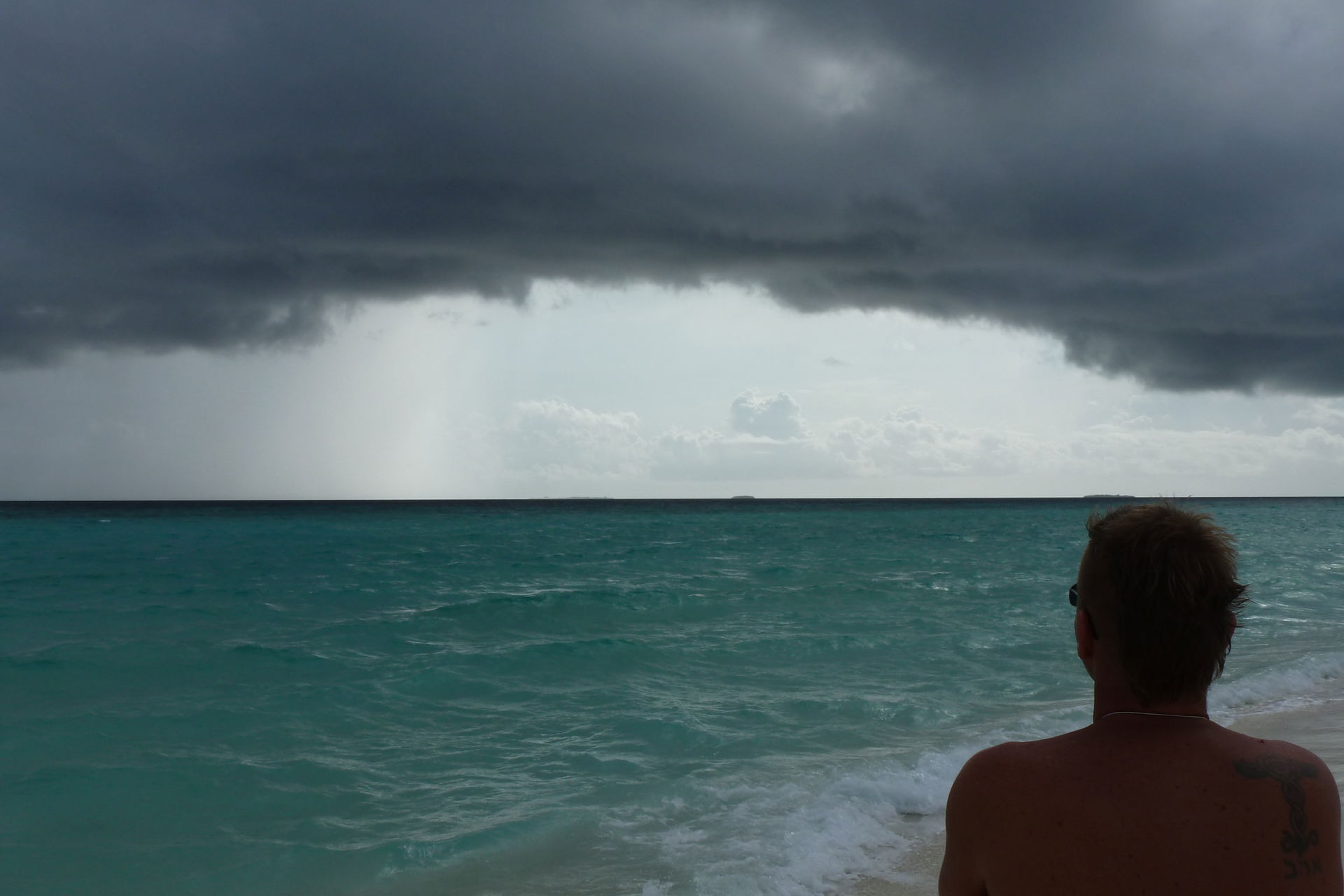 Man looking at very dense clouds and the rough sea. The locatio…