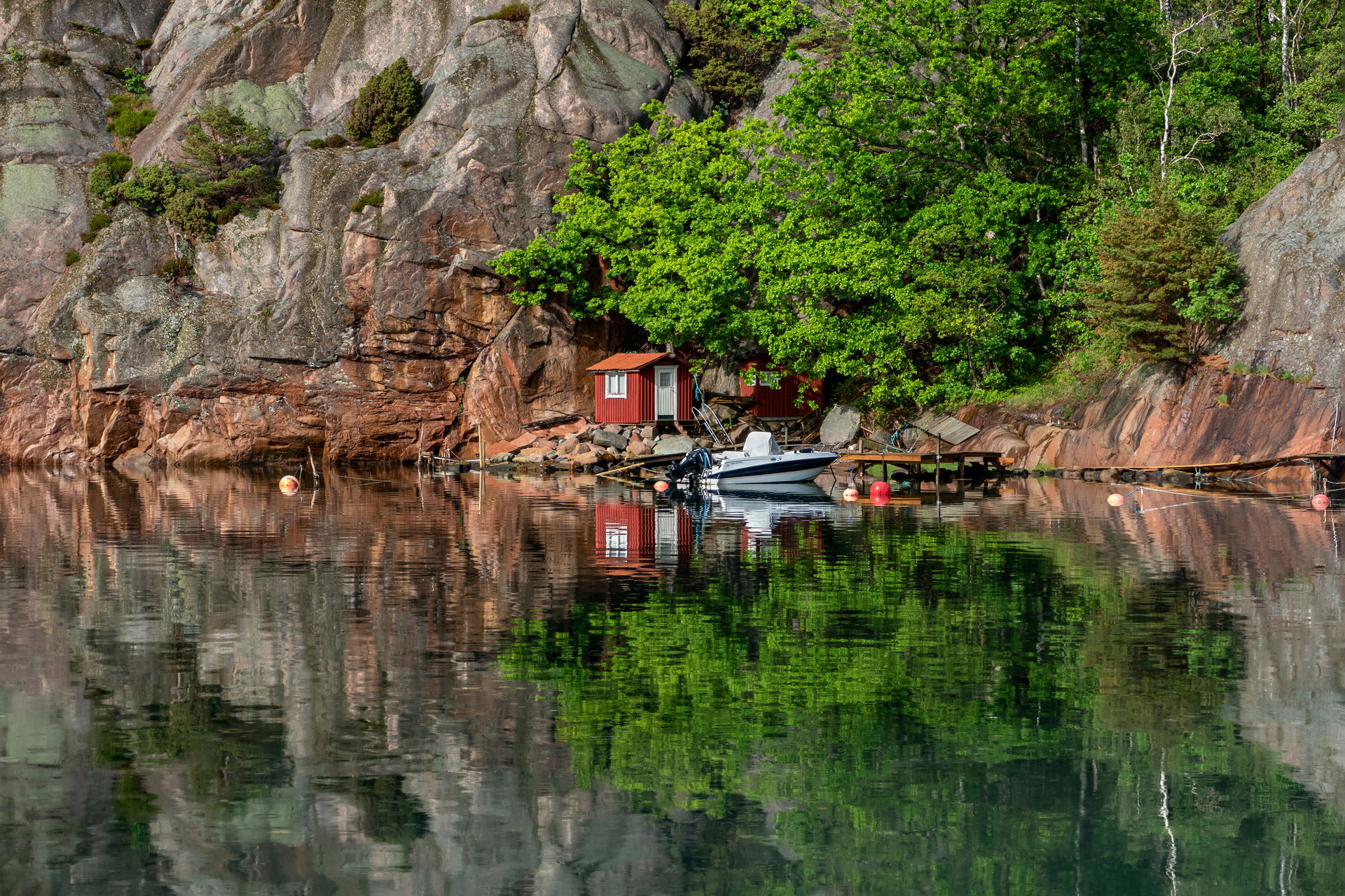 Two Falu red fishing huts and a motorboat by the cliff in Rågår…