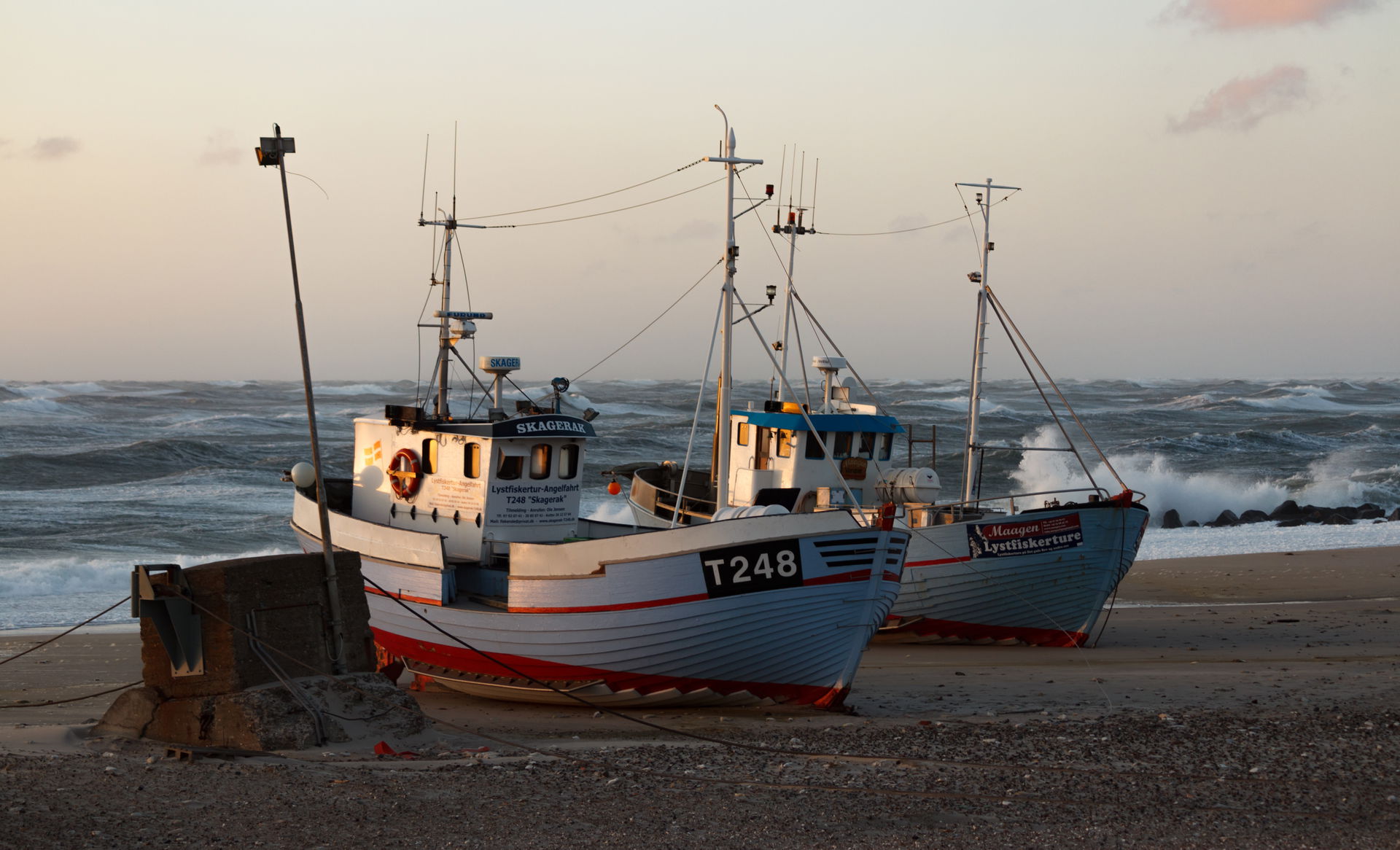 Two beached fishing vessels at sunset at Nørre Vorupør, Denmark