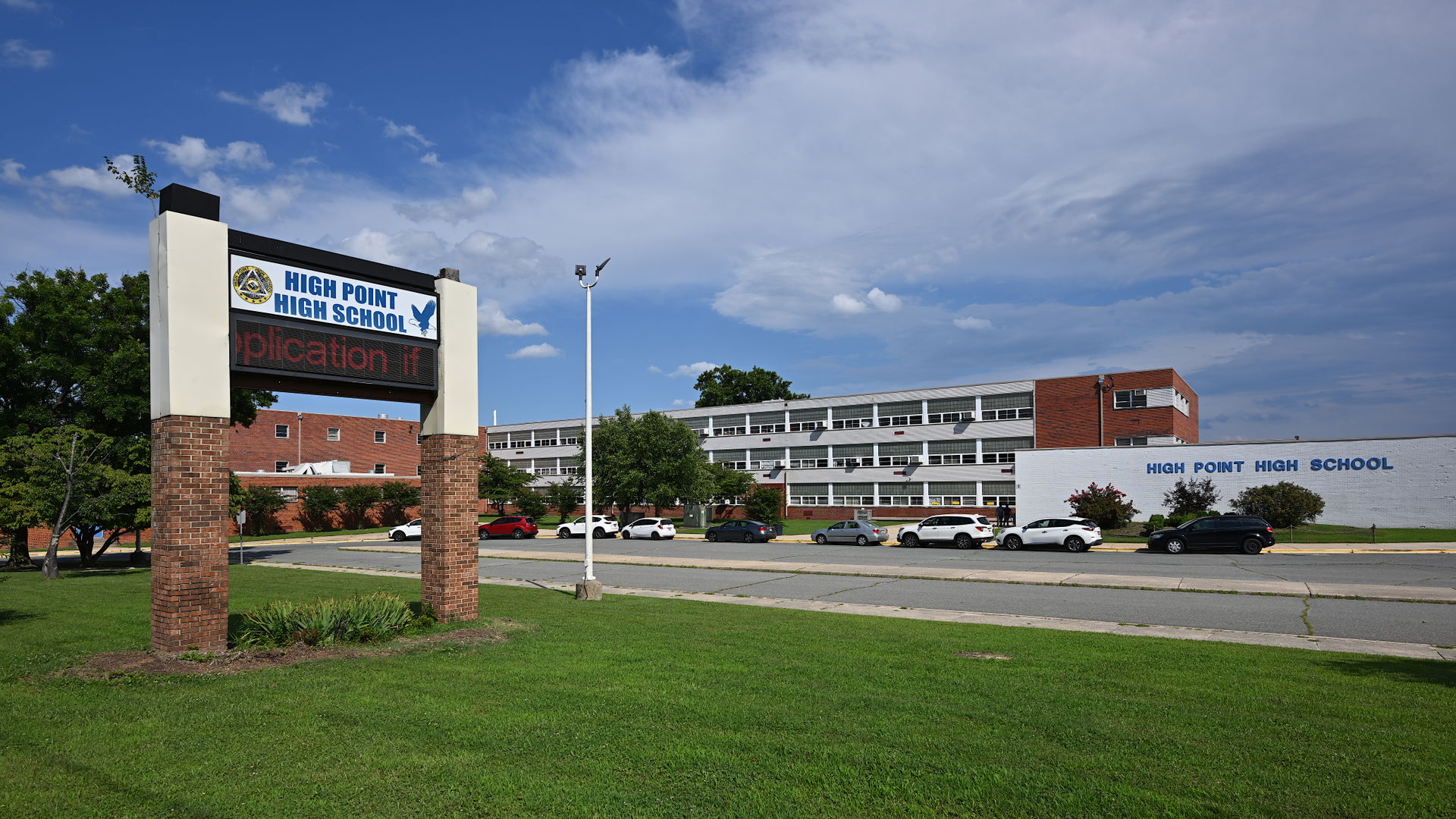 The sign for High Point High School with the main building behi…