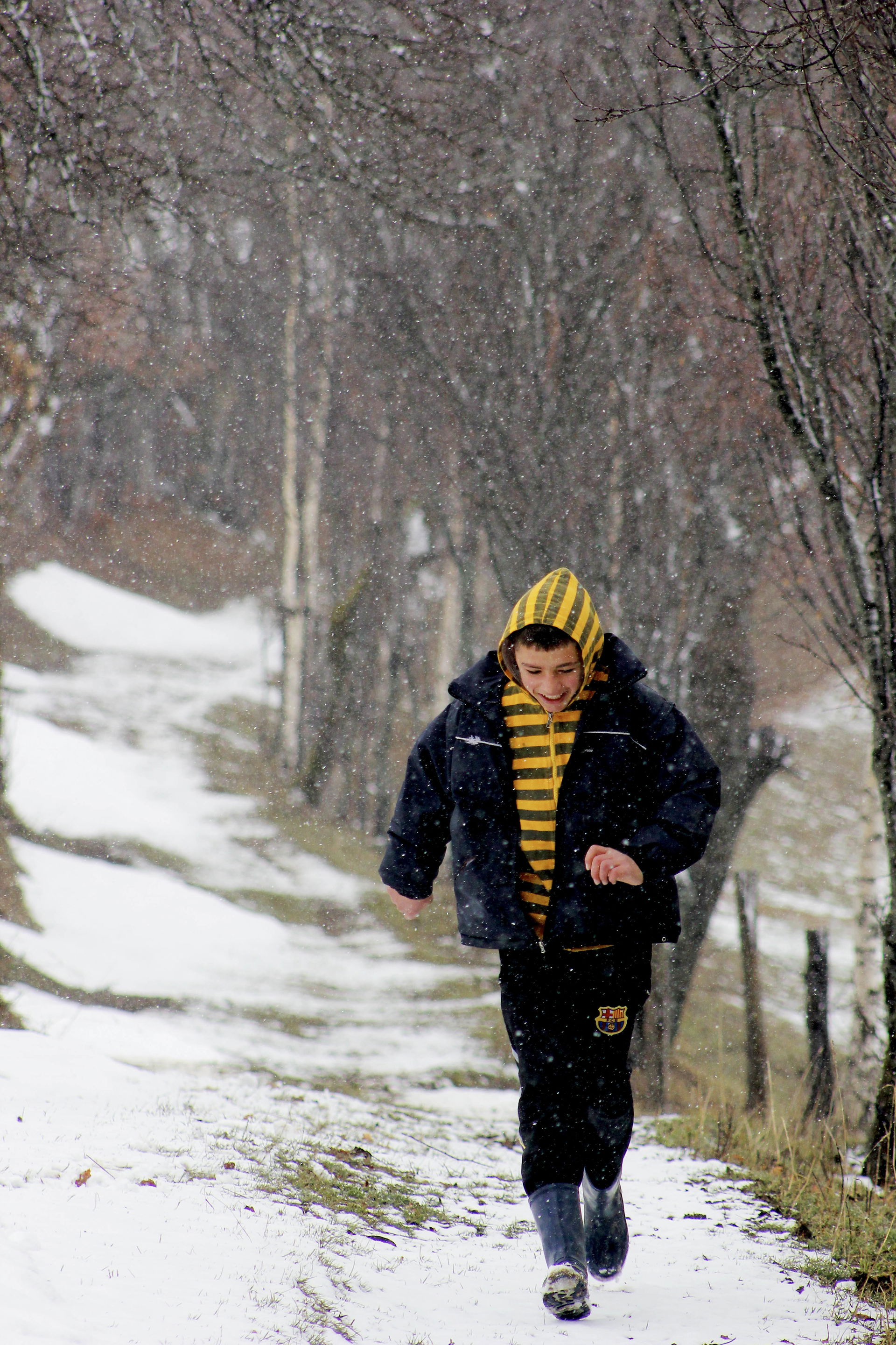 Një djalë i ri vrapon i lumtur në fluskat e para të borës, fsha…